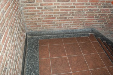 <p>In de gangen en het trappenhuis zijn de plinten uitgevoerd in terrazzo, de tegelvloer is een latere verandering. Oorspronkelijk lagen hier plavuizen 15 x 15 cm. </p>
